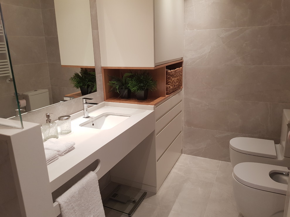 Imagen de cuarto de baño principal minimalista de tamaño medio con puertas de armario blancas, baldosas y/o azulejos grises, paredes grises, lavabo suspendido, suelo gris y encimeras blancas