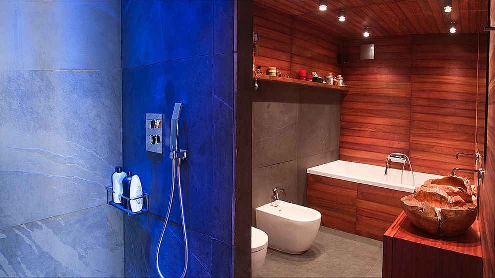 Diseño de cuarto de baño campestre de tamaño medio con puertas de armario de madera oscura, bañera empotrada, bidé, aseo y ducha, lavabo sobreencimera y encimera de madera