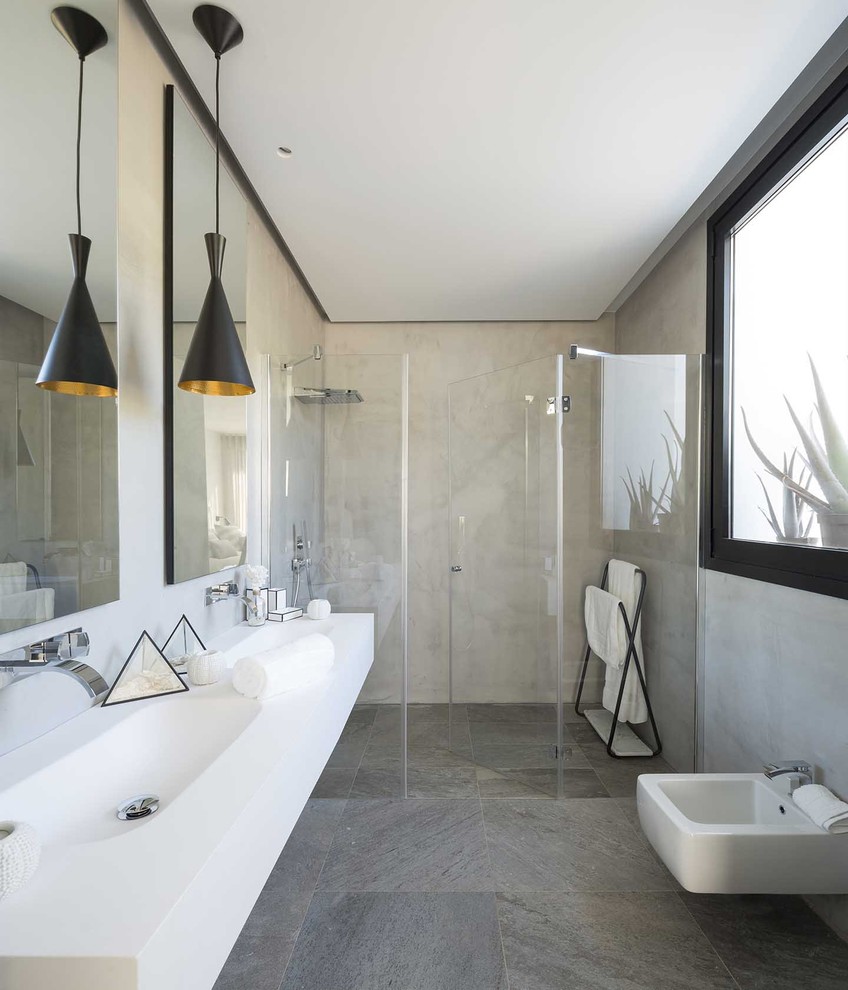 Diseño de cuarto de baño escandinavo con ducha a ras de suelo, aseo y ducha, lavabo integrado, suelo gris, ducha con puerta con bisagras y encimeras blancas