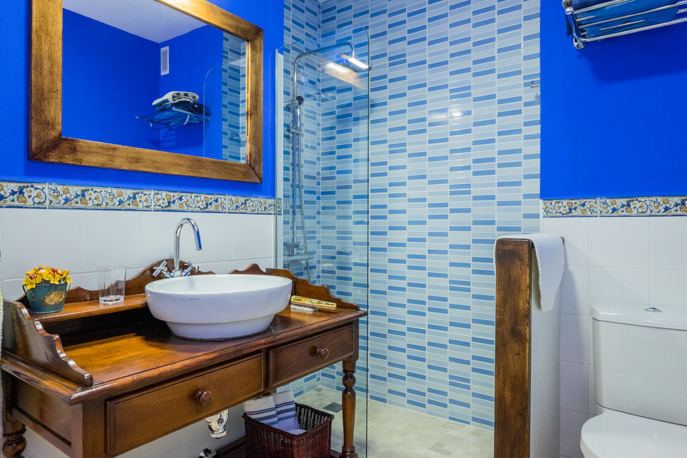 Ejemplo de cuarto de baño costero de tamaño medio con armarios tipo mueble, puertas de armario de madera en tonos medios, ducha esquinera, sanitario de dos piezas, paredes azules, aseo y ducha y lavabo sobreencimera