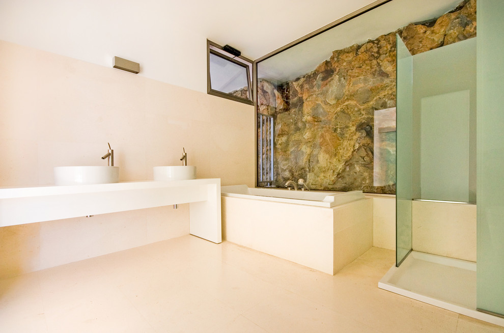 Modelo de cuarto de baño principal mediterráneo grande con bañera encastrada, ducha esquinera, lavabo sobreencimera y paredes beige
