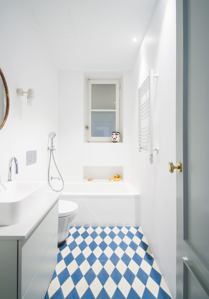Ejemplo de cuarto de baño azulejo de dos tonos actual con armarios con paneles lisos, puertas de armario blancas, bañera empotrada, combinación de ducha y bañera, paredes blancas, lavabo sobreencimera, suelo multicolor y encimeras blancas
