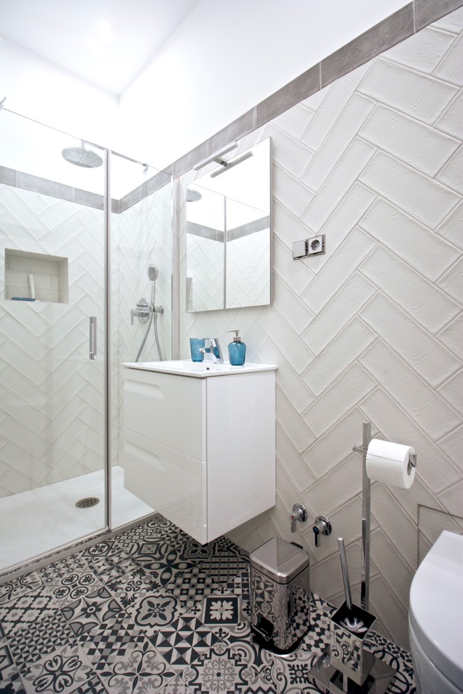 Aménagement d'une salle d'eau scandinave avec des portes de placard blanches, un plan de toilette blanc, WC suspendus, un carrelage gris, un carrelage blanc, un sol multicolore et une cabine de douche à porte battante.