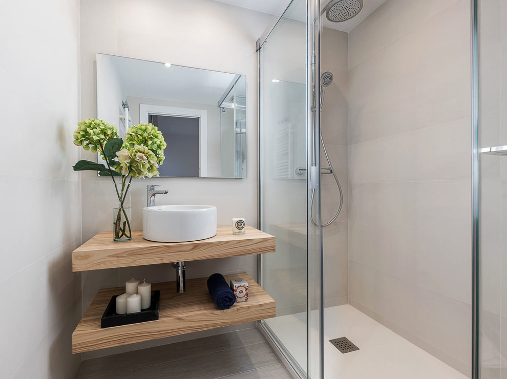 Modelo de cuarto de baño escandinavo con armarios abiertos, ducha empotrada, baldosas y/o azulejos beige, lavabo sobreencimera, encimera de madera, suelo beige, ducha con puerta con bisagras y encimeras beige