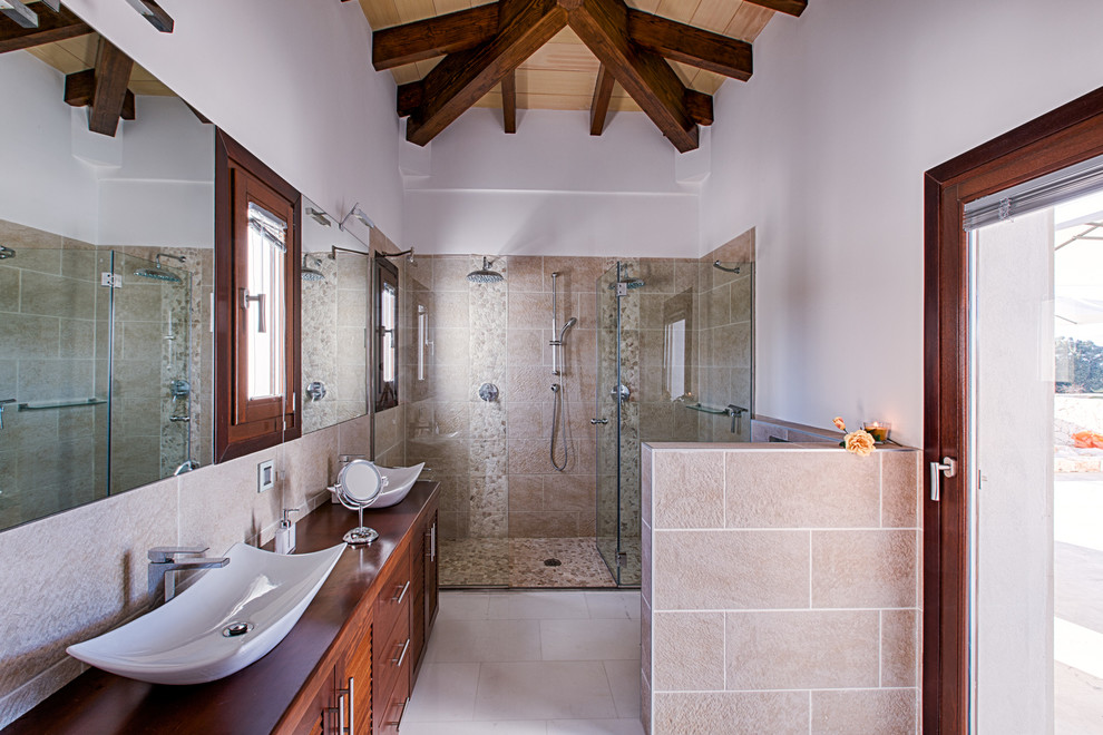 Inspiration för ett mellanstort rustikt badrum med dusch, med luckor med upphöjd panel, skåp i mörkt trä, en dubbeldusch, vita väggar, ett fristående handfat, beige kakel, stenkakel och träbänkskiva