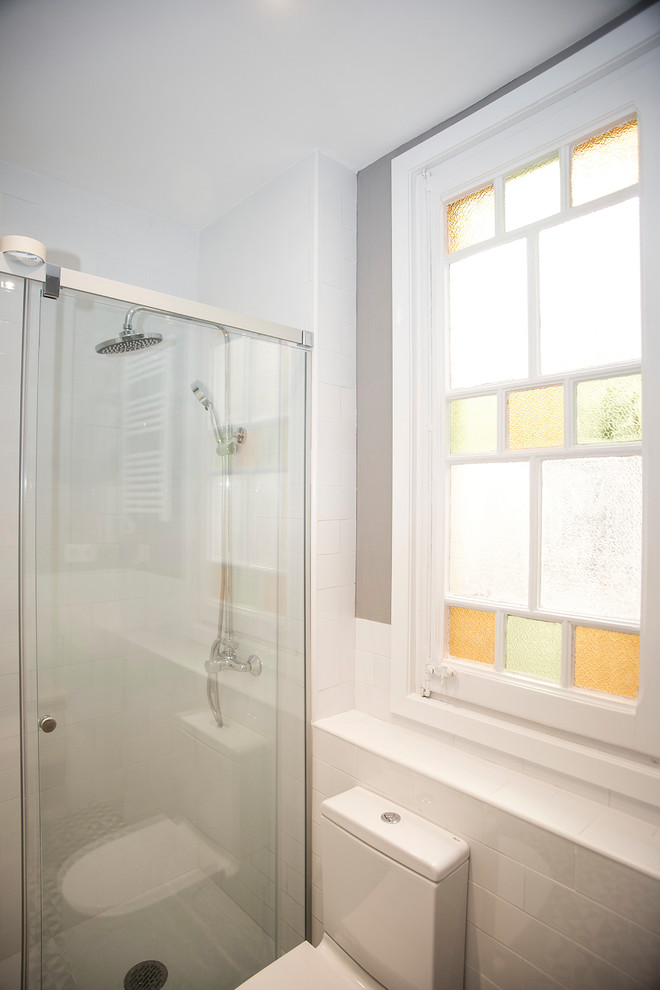 Modern inredning av ett mellanstort en-suite badrum, med skåp i mellenmörkt trä, en dusch i en alkov, en toalettstol med hel cisternkåpa, vit kakel, vita väggar, ett fristående handfat, flerfärgat golv och dusch med skjutdörr