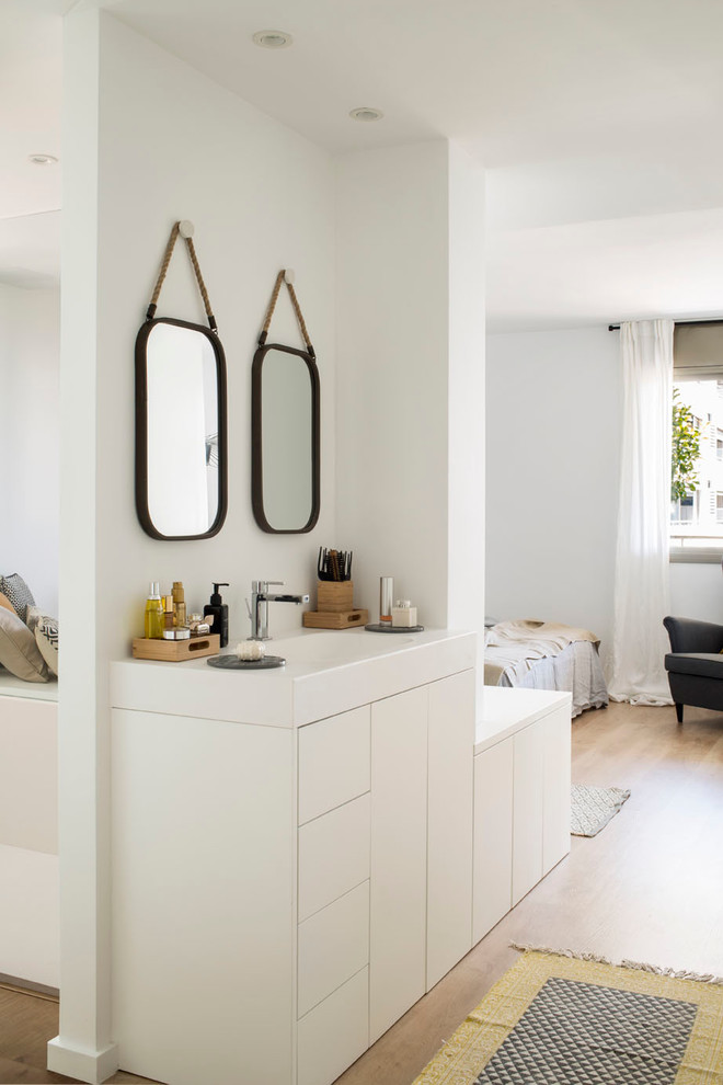 Kleines Modernes Badezimmer En Suite mit weißen Schränken, weißen Fliesen, weißer Wandfarbe, braunem Holzboden, integriertem Waschbecken und flächenbündigen Schrankfronten in Barcelona