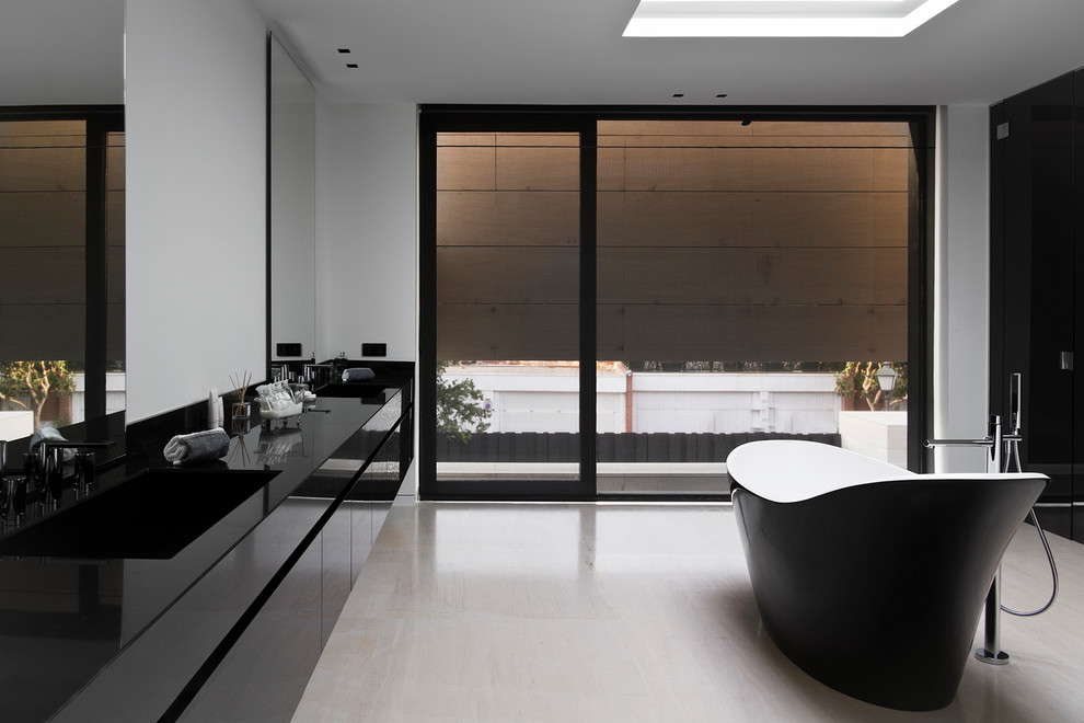 Großes Modernes Badezimmer En Suite mit flächenbündigen Schrankfronten, schwarzen Schränken, freistehender Badewanne, Duschbadewanne, weißer Wandfarbe, Travertin, integriertem Waschbecken und Mineralwerkstoff-Waschtisch in Madrid