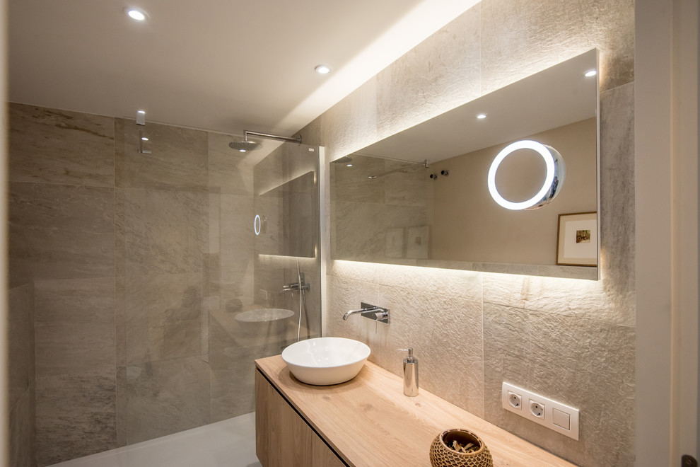 Idéer för att renovera ett mellanstort funkis en-suite badrum, med släta luckor, skåp i ljust trä, en öppen dusch, en toalettstol med hel cisternkåpa, grå kakel, grå väggar, laminatgolv, ett fristående handfat, träbänkskiva och med dusch som är öppen