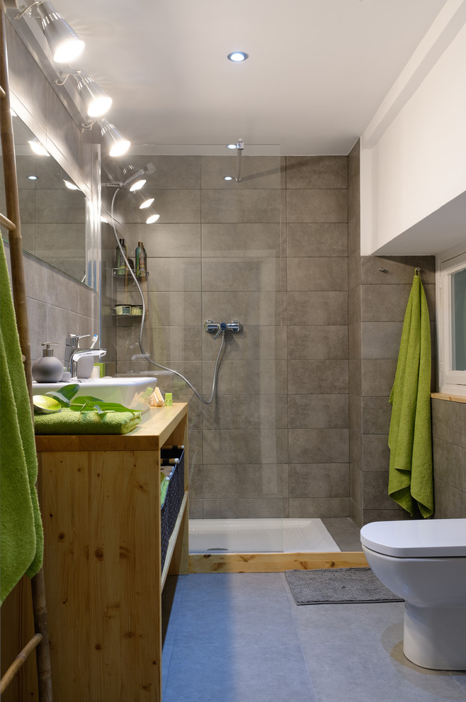 Esempio di una stanza da bagno con doccia scandinava di medie dimensioni con nessun'anta, ante in legno scuro, doccia aperta, WC monopezzo, pareti grigie, lavabo a bacinella e top in legno