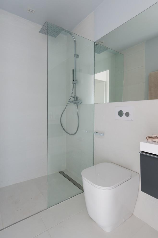 Foto de cuarto de baño contemporáneo de tamaño medio con armarios con paneles lisos, puertas de armario grises, ducha a ras de suelo, sanitario de una pieza, paredes blancas, aseo y ducha y lavabo integrado