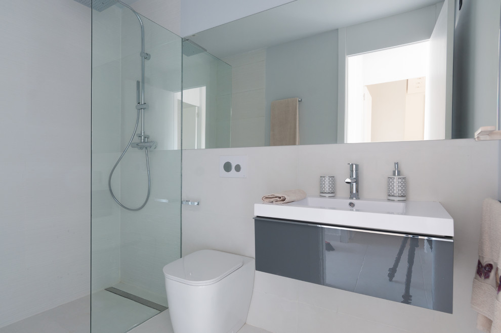 Réalisation d'une salle d'eau design de taille moyenne avec un placard à porte plane, des portes de placard grises, une douche à l'italienne, WC à poser, un mur blanc et un lavabo intégré.