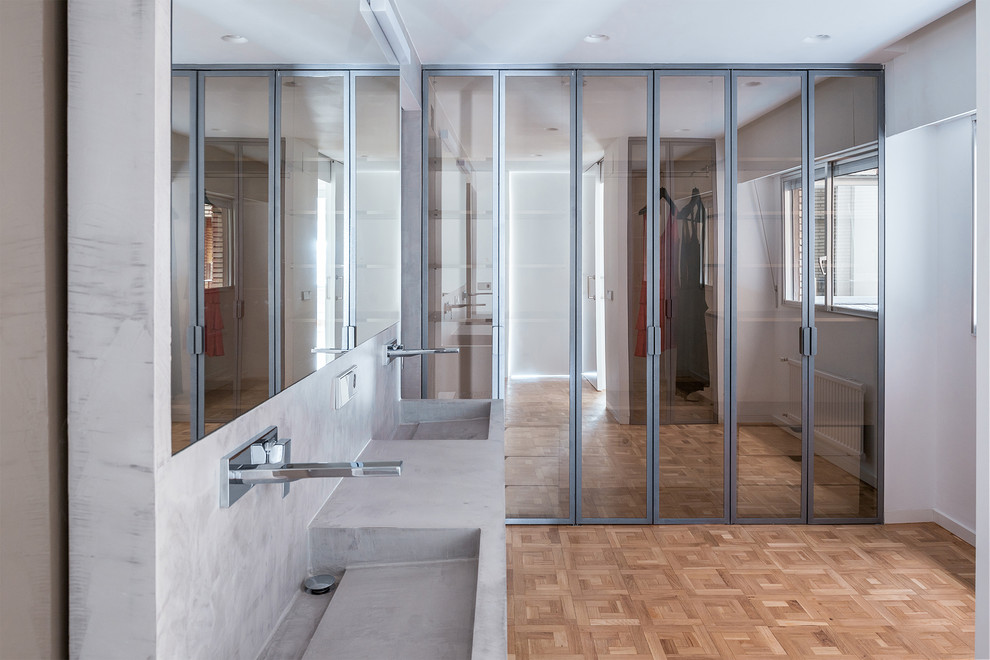Cette image montre une grande salle de bain principale design avec un placard à porte vitrée, une douche à l'italienne, WC à poser, un mur gris, parquet clair, un lavabo suspendu et une cabine de douche à porte coulissante.