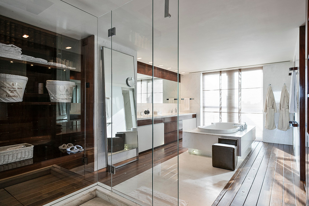Esempio di un'ampia stanza da bagno padronale design con parquet scuro, ante lisce, ante in legno bruno, vasca da incasso, doccia ad angolo e pareti bianche