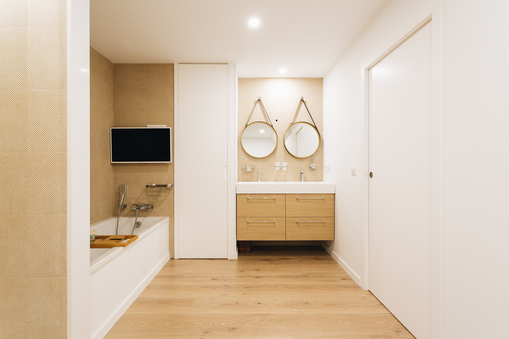 Esempio di un'ampia stanza da bagno padronale minimalista con consolle stile comò, ante in legno chiaro, vasca ad alcova, doccia alcova, piastrelle beige, piastrelle in ceramica, pareti beige, lavabo sospeso e top bianco