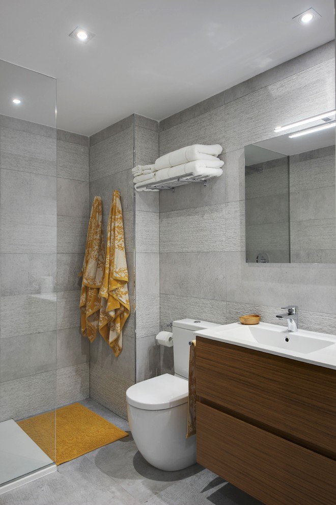 Cette image montre une salle de bain grise et jaune design en bois foncé avec un placard à porte plane, une douche à l'italienne, WC séparés, un carrelage gris, un plan vasque et aucune cabine.