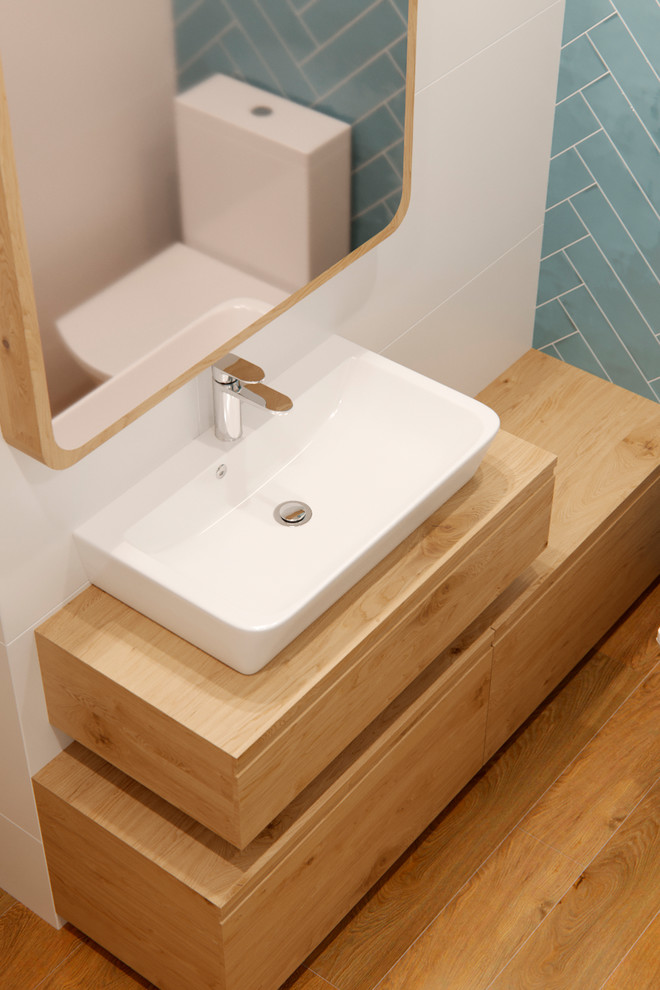 Idéer för små skandinaviska en-suite badrum, med möbel-liknande, skåp i ljust trä, ett platsbyggt badkar, blå kakel, keramikplattor, vita väggar, träbänkskiva och dusch med skjutdörr