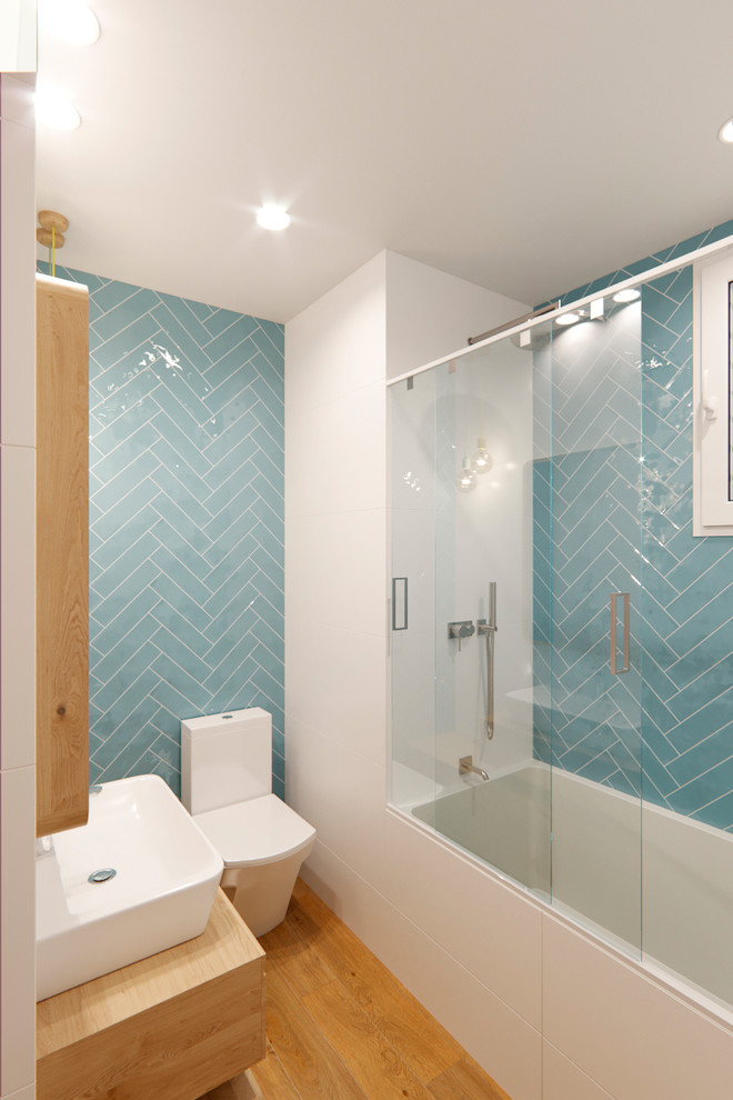Ispirazione per una piccola stanza da bagno padronale scandinava con consolle stile comò, ante in legno chiaro, vasca da incasso, piastrelle blu, piastrelle in ceramica, pareti bianche, top in legno e porta doccia scorrevole