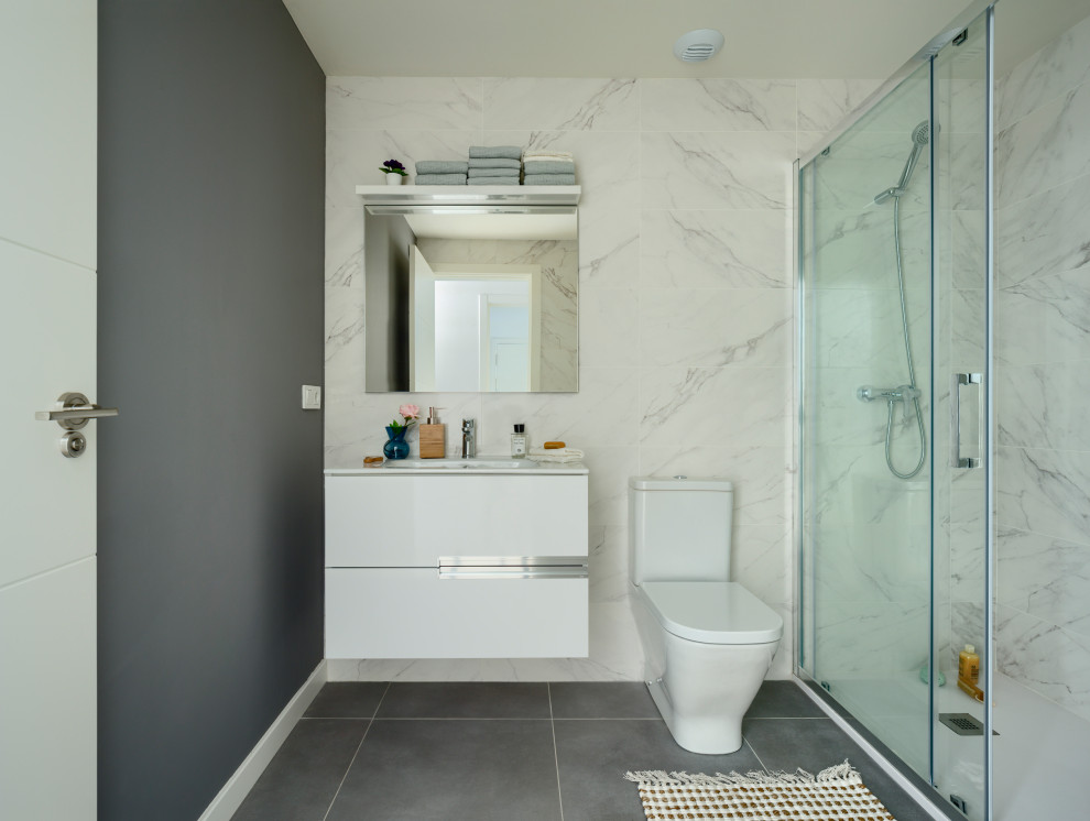 Foto på ett litet tropiskt vit badrum med dusch, med släta luckor, vita skåp, en kantlös dusch, vit kakel, keramikplattor, ett nedsänkt handfat, bänkskiva i kvarts och grått golv