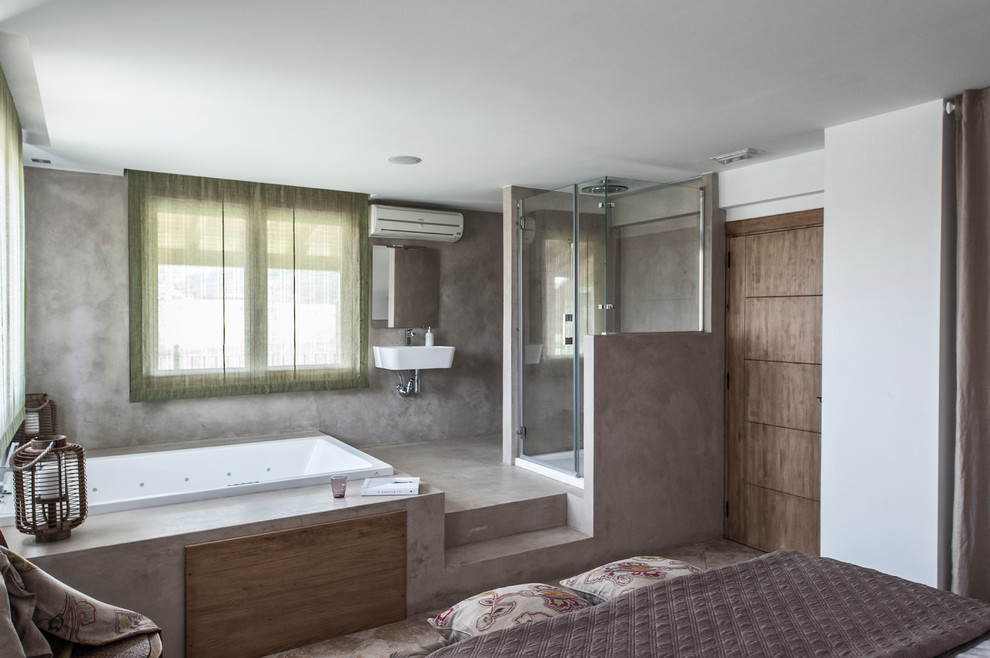 Modelo de cuarto de baño principal mediterráneo de tamaño medio con jacuzzi, ducha empotrada, paredes grises y suelo de cemento