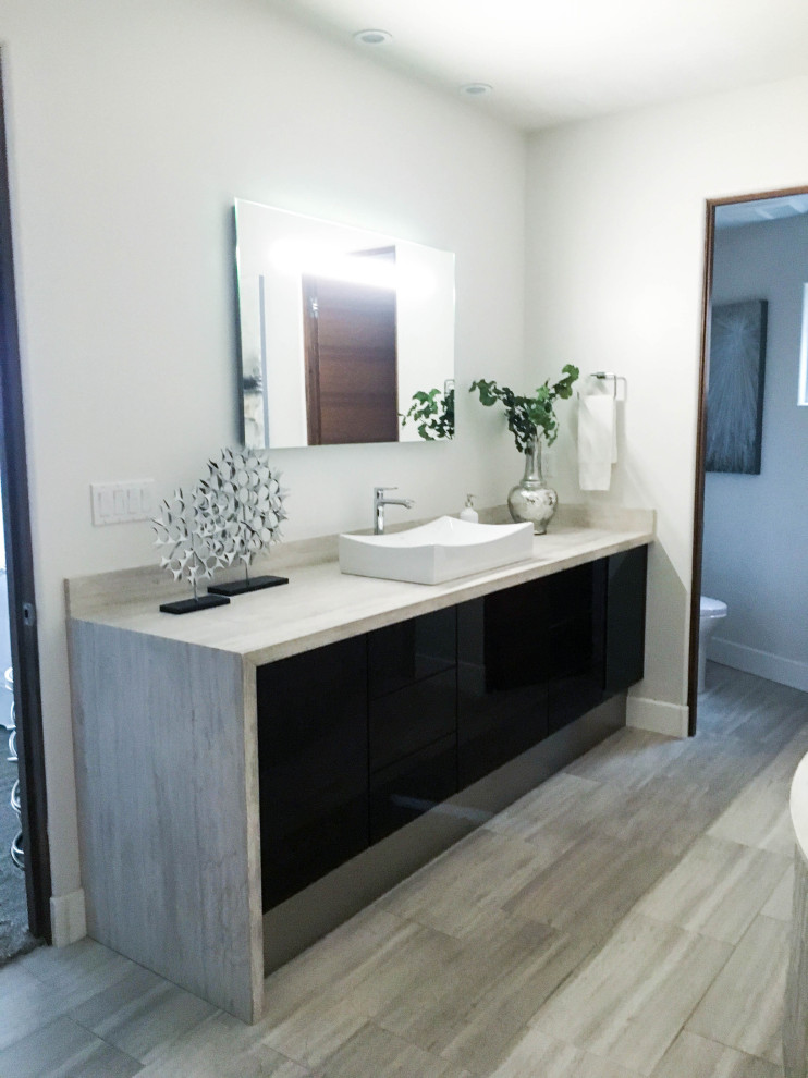 サンディエゴにあるコンテンポラリースタイルのおしゃれな浴室 (フラットパネル扉のキャビネット、黒いキャビネット、ドロップイン型浴槽、磁器タイル、白い壁、ベッセル式洗面器、グレーの床、グレーのタイル、グレーの洗面カウンター) の写真