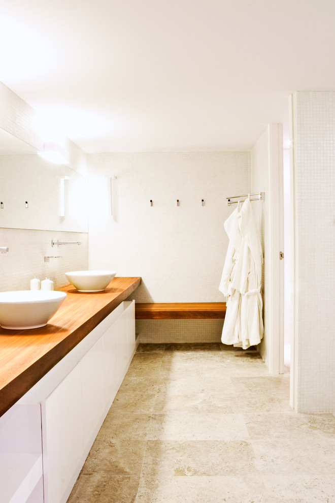 Inspiration för mellanstora moderna badrum med dusch, med släta luckor, vita skåp, vita väggar, travertin golv, ett fristående handfat och träbänkskiva