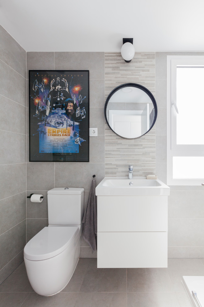 Foto på ett skandinaviskt badrum för barn, med vita skåp, grå kakel, flerfärgad kakel, släta luckor, en toalettstol med separat cisternkåpa, stickkakel, grå väggar och grått golv