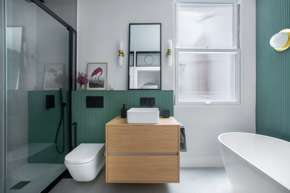 Ejemplo de cuarto de baño principal, único, flotante y rectangular con armarios con paneles lisos, puertas de armario de madera oscura, bañera exenta, ducha empotrada, sanitario de pared, baldosas y/o azulejos grises, paredes blancas, lavabo sobreencimera, encimera de madera, suelo gris, encimeras marrones y panelado