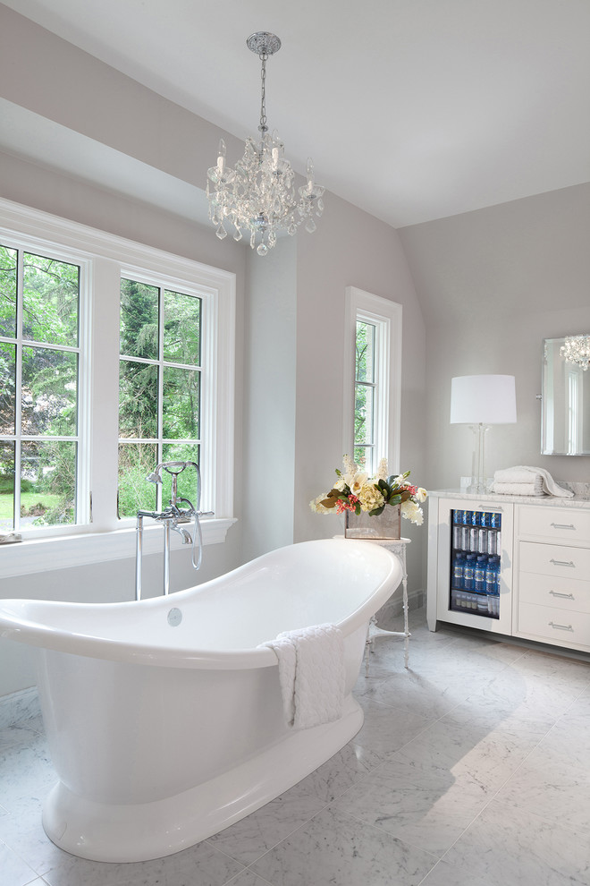 Идея дизайна: главная ванная комната среднего размера в классическом стиле с плоскими фасадами, белыми фасадами, отдельно стоящей ванной, душем над ванной, серыми стенами и накладной раковиной