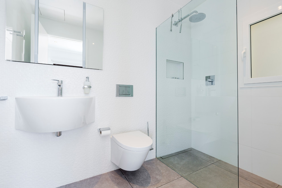 Diseño de cuarto de baño de tamaño medio con ducha a ras de suelo, lavabo suspendido, baldosas y/o azulejos blancos, baldosas y/o azulejos de porcelana, paredes blancas y aseo y ducha