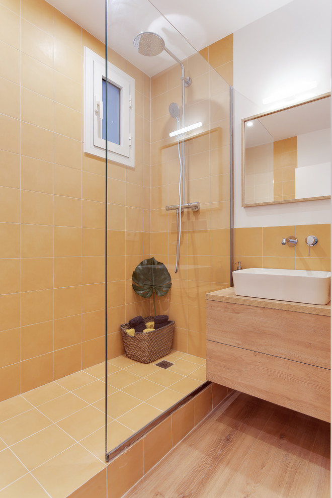 Modernes Badezimmer mit flächenbündigen Schrankfronten, hellen Holzschränken, orangen Fliesen, weißer Wandfarbe, hellem Holzboden, Aufsatzwaschbecken, Waschtisch aus Holz, beigem Boden, offener Dusche und brauner Waschtischplatte in Barcelona