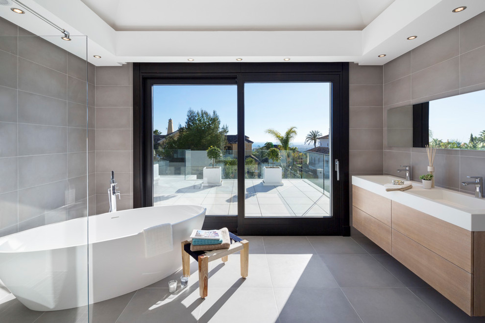 Ispirazione per una grande stanza da bagno padronale contemporanea con ante lisce, ante in legno scuro, vasca freestanding e lavabo integrato