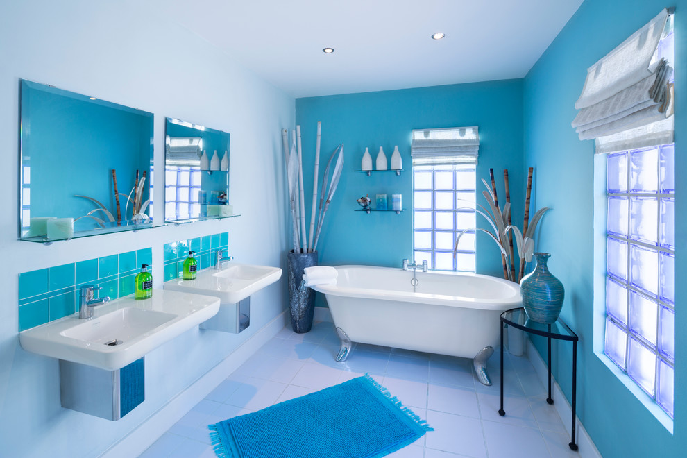 На фото: главная ванная комната среднего размера в стиле фьюжн с ванной на ножках, душем над ванной, синими стенами и подвесной раковиной с