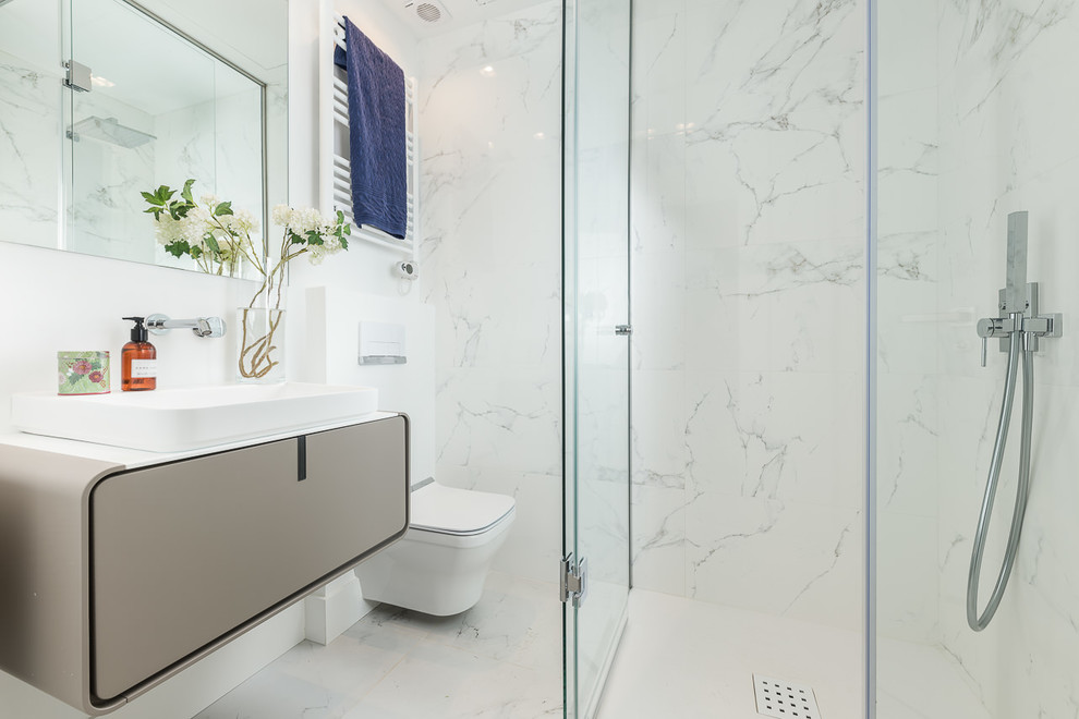 Foto på ett litet minimalistiskt vit badrum med dusch, med möbel-liknande, beige skåp, en hörndusch, en vägghängd toalettstol, vit kakel, keramikplattor, vita väggar, klinkergolv i keramik, ett integrerad handfat, bänkskiva i akrylsten, vitt golv och dusch med gångjärnsdörr