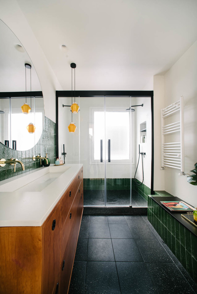 Идея дизайна: ванная комната в современном стиле с фасадами цвета дерева среднего тона, белыми стенами, душевой кабиной, черным полом, душем с раздвижными дверями, белой столешницей, душем в нише, зеленой плиткой, раковиной с несколькими смесителями и плоскими фасадами