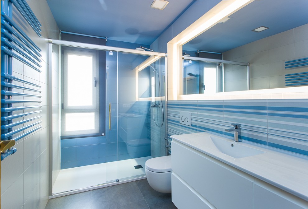 Foto på ett mellanstort maritimt en-suite badrum, med släta luckor, vita skåp, en dusch i en alkov, en vägghängd toalettstol, flerfärgade väggar, klinkergolv i keramik, ett integrerad handfat, flerfärgad kakel och keramikplattor