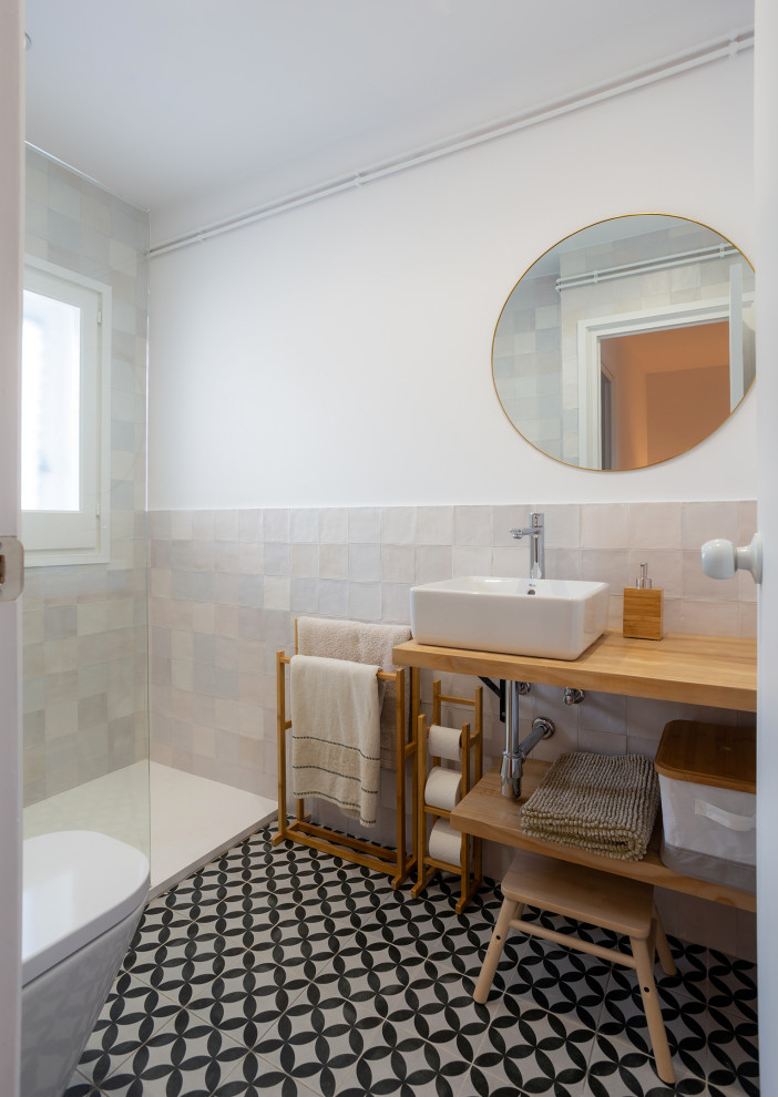 На фото: главная ванная комната среднего размера в средиземноморском стиле с открытыми фасадами, белыми фасадами, душем в нише, унитазом-моноблоком, разноцветной плиткой, керамической плиткой, разноцветными стенами, полом из керамической плитки, настольной раковиной, столешницей из дерева, разноцветным полом, открытым душем, коричневой столешницей и подвесной тумбой с