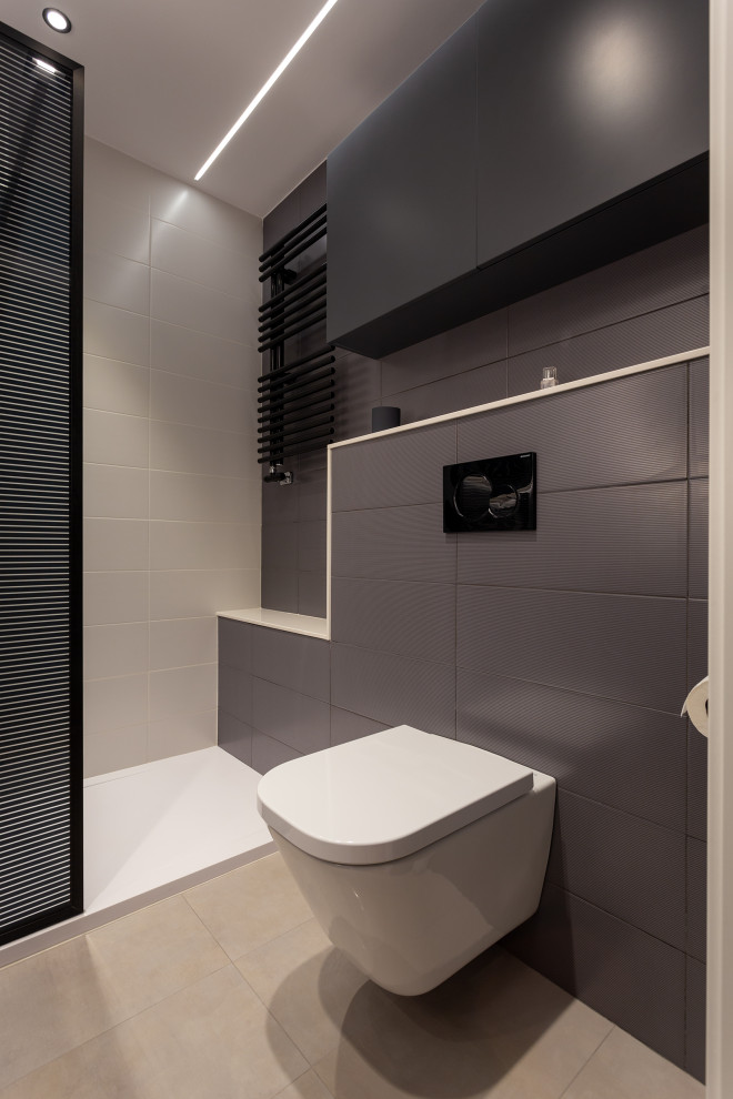 Modelo de cuarto de baño contemporáneo de tamaño medio con puertas de armario negras, ducha empotrada, sanitario de pared, baldosas y/o azulejos beige, paredes beige, lavabo sobreencimera y encimeras beige