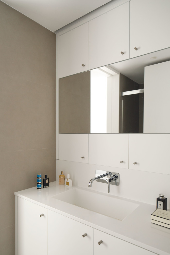 Immagine di una stanza da bagno scandinava con ante lisce, ante bianche, pareti grigie, lavabo integrato e top bianco