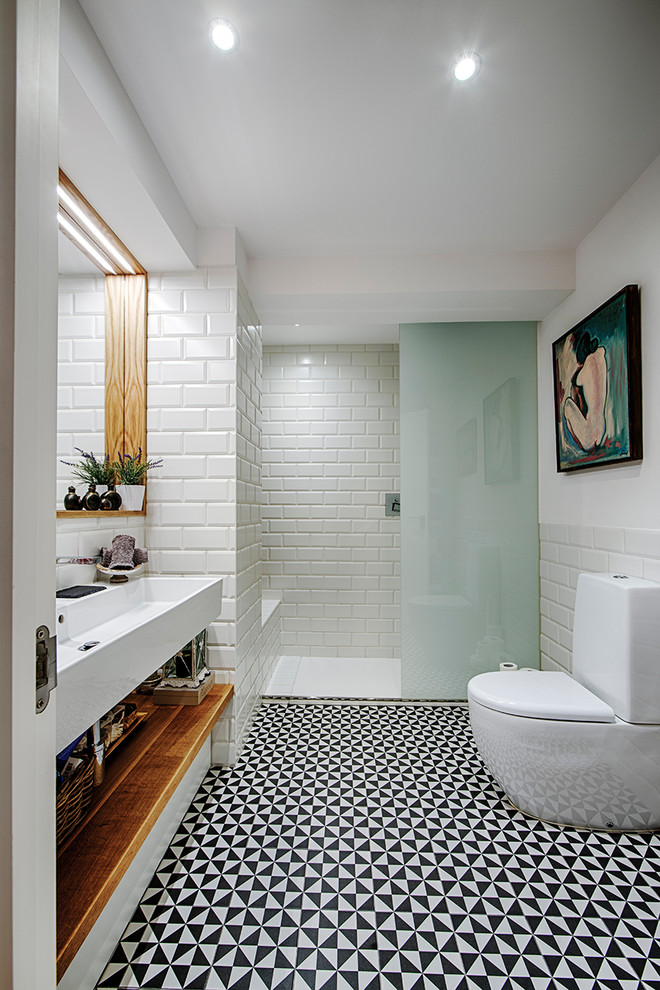 Стильный дизайн: ванная комната среднего размера в современном стиле с писсуаром, белой плиткой, белыми стенами, душевой кабиной, раковиной с несколькими смесителями и зеркалом с подсветкой - последний тренд