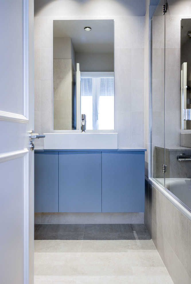 Idée de décoration pour une petite salle de bain design avec un placard à porte plane, des portes de placard bleues, un mur beige et une vasque.