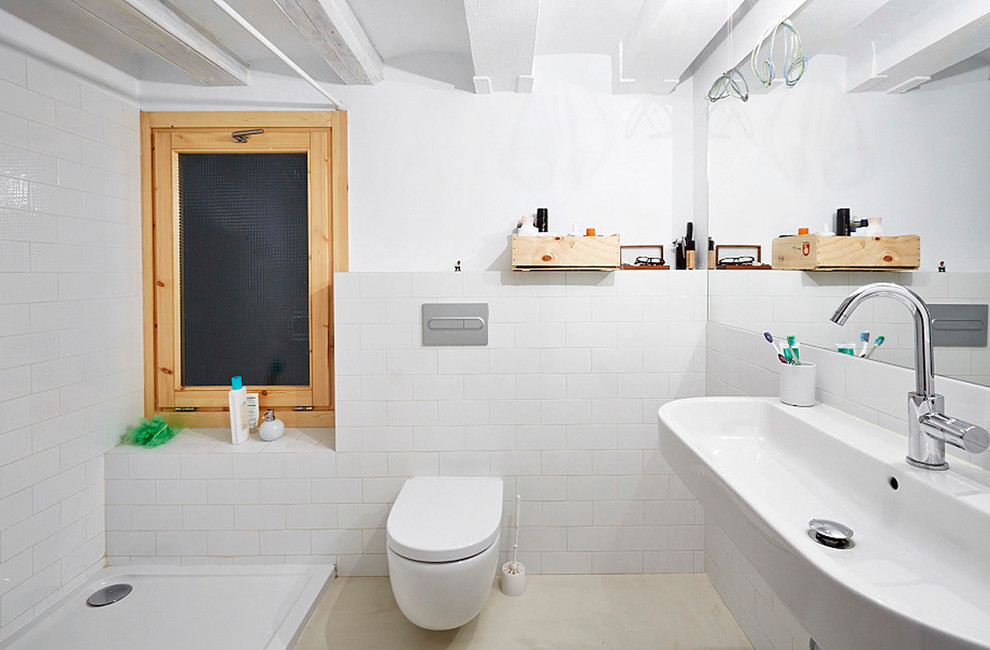 Imagen de cuarto de baño escandinavo de tamaño medio con ducha abierta, sanitario de pared, baldosas y/o azulejos blancos, baldosas y/o azulejos de cerámica, paredes blancas, aseo y ducha y lavabo de seno grande