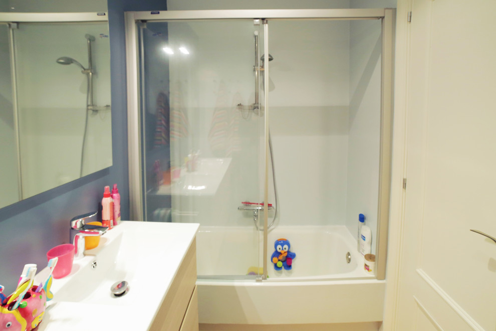 Bild på ett mellanstort funkis badrum för barn, med släta luckor, skåp i ljust trä, ett platsbyggt badkar, blå väggar, klinkergolv i keramik, ett väggmonterat handfat, bänkskiva i akrylsten och gult golv