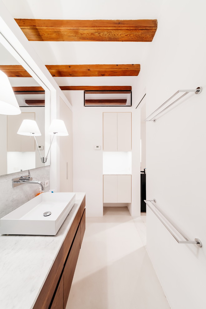 Modelo de cuarto de baño principal actual de tamaño medio con armarios con paneles lisos, puertas de armario blancas, paredes blancas, suelo de cemento, lavabo sobreencimera, encimera de mármol y suelo gris