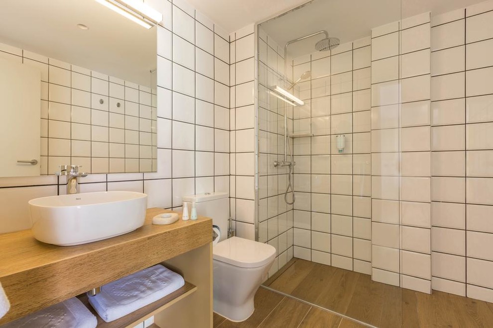 Idéer för att renovera ett litet minimalistiskt en-suite badrum, med öppna hyllor, en dusch i en alkov, en toalettstol med hel cisternkåpa, vit kakel, keramikplattor, vita väggar, mellanmörkt trägolv, ett fristående handfat, träbänkskiva, brunt golv, med dusch som är öppen och skåp i mellenmörkt trä
