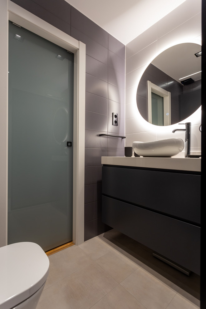 Exempel på ett mellanstort modernt grå grått badrum med dusch, med släta luckor, svarta skåp, en vägghängd toalettstol, grå kakel, porslinskakel, klinkergolv i porslin, ett fristående handfat och grått golv