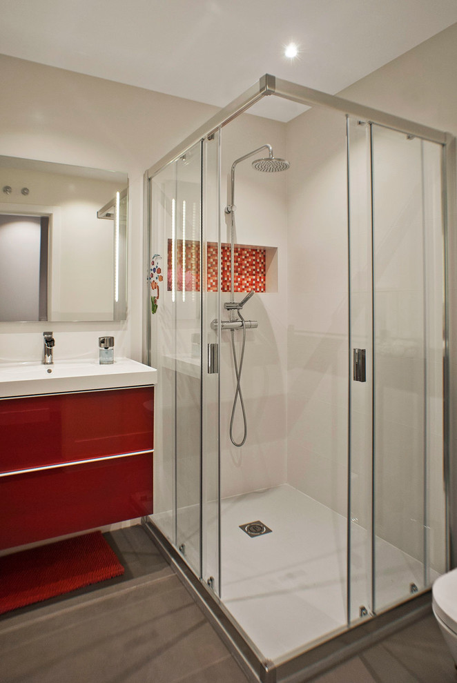 Inspiration for a medium sized contemporary family bathroom in Madrid with a corner shower, grey tiles, porcelain tiles, white walls, porcelain flooring, a trough sink, flat-panel cabinets and red cabinets.