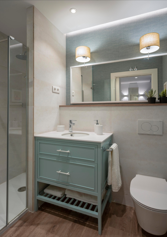 Klassisk inredning av ett mellanstort vit vitt badrum med dusch, med möbel-liknande, vita skåp, en kantlös dusch, en vägghängd toalettstol, beige kakel, porslinskakel, beige väggar, laminatgolv, ett undermonterad handfat, bänkskiva i kvarts, brunt golv och dusch med gångjärnsdörr