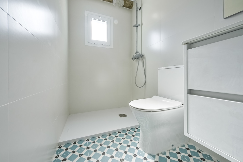 Idéer för att renovera ett mellanstort funkis vit vitt en-suite badrum, med släta luckor, vita skåp, en dusch i en alkov, en toalettstol med separat cisternkåpa, vit kakel, porslinskakel, vita väggar, klinkergolv i keramik, ett integrerad handfat, blått golv och med dusch som är öppen