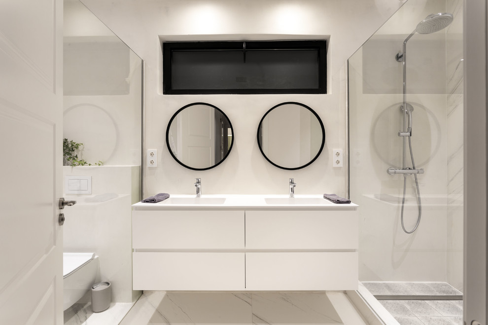 Inspiration för ett funkis vit vitt badrum med dusch, med släta luckor, en kantlös dusch, en vägghängd toalettstol, vit kakel, vita väggar, ett integrerad handfat, vita skåp och vitt golv